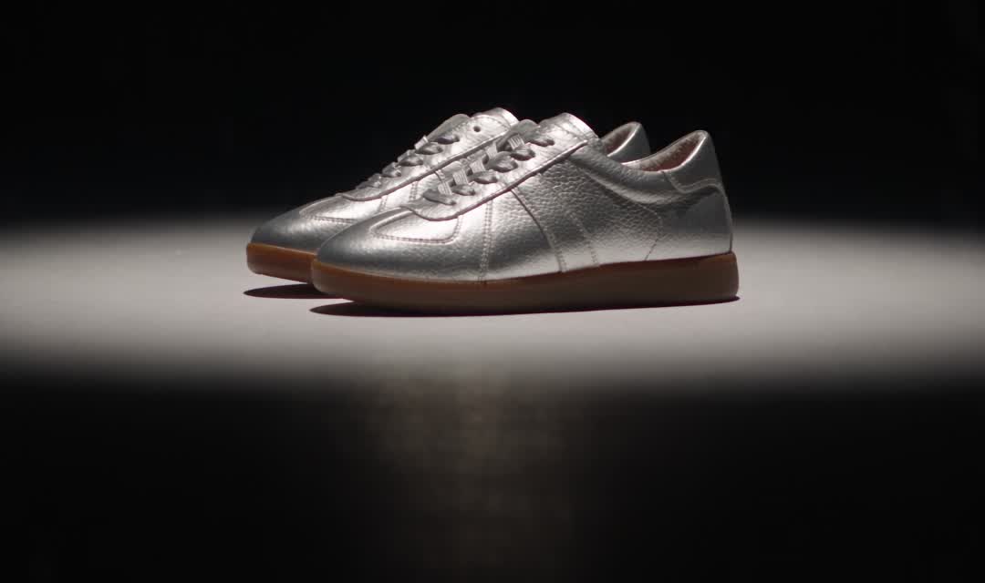 Silver trainers under a single spotlight on black